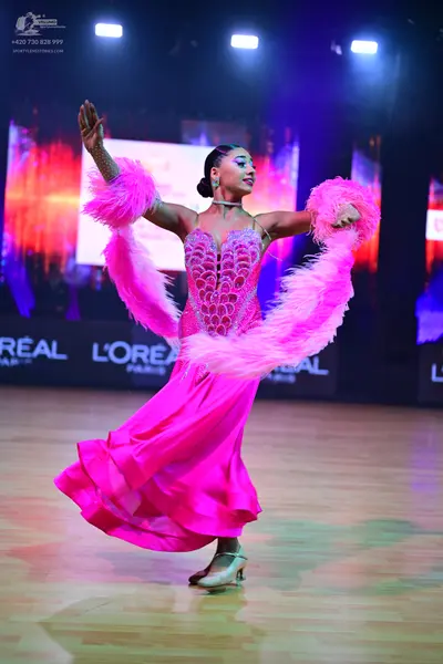 Dancesport competitor: Female dancer: bright pink ballroom dress with a heavily sequined/rhinestone-enc
