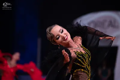 Dancesport competitor: Female dancer: black and nude latin dress with gold and green sequin patterns an