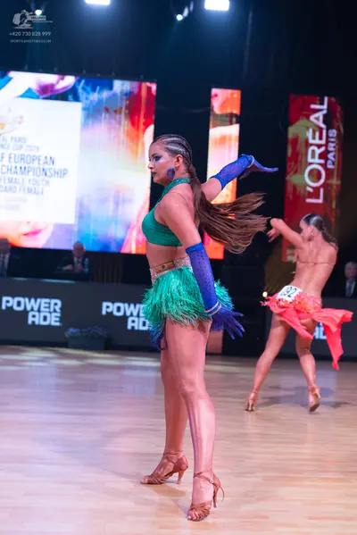 Dancesport competitor: Female dancer 1: teal/green Latin dance costume with a crop top, a fringed skirt