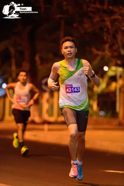 Marathon runner #42143: Runner 1: white and green tank top, dark grey shorts, light blue and pink shoes,