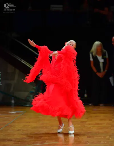 Dancesport competitor: Female dancer: red Latin dress with heavy fringe/feathers on the sleeves and ski