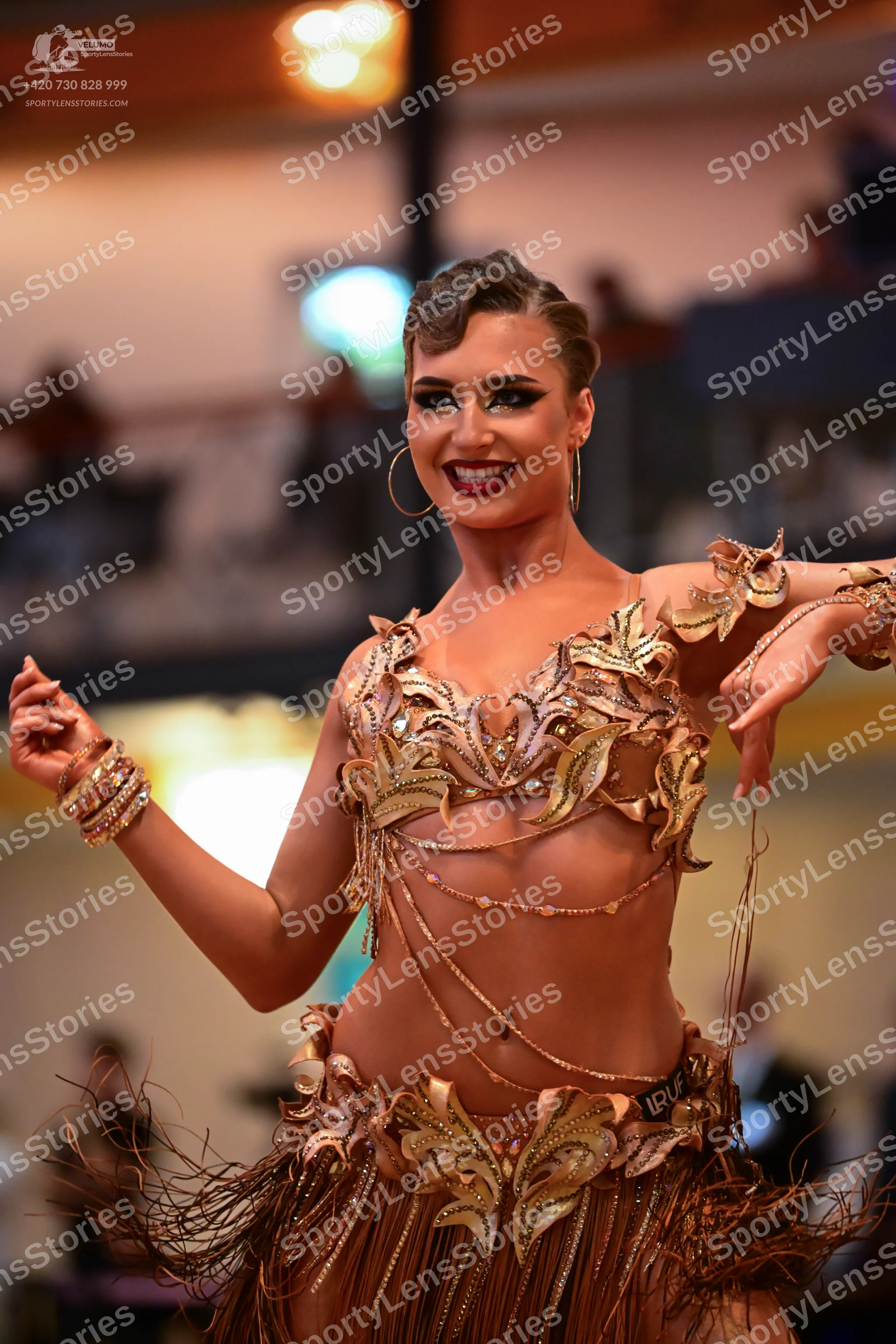 Dancesport competitor: Female dancer: gold/bronze latin dance costume featuring sequined leaf-like appl