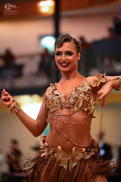 Dancesport competitor: Female dancer: gold/bronze latin dance costume featuring sequined leaf-like appl