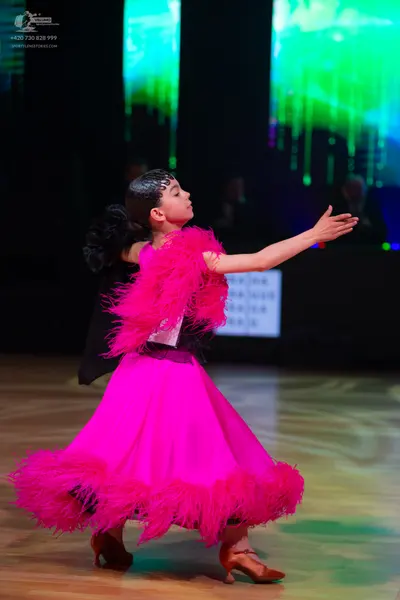 Dancesport competitor: Female dancer: pink Latin dress with large pink feather trim on the bodice and s