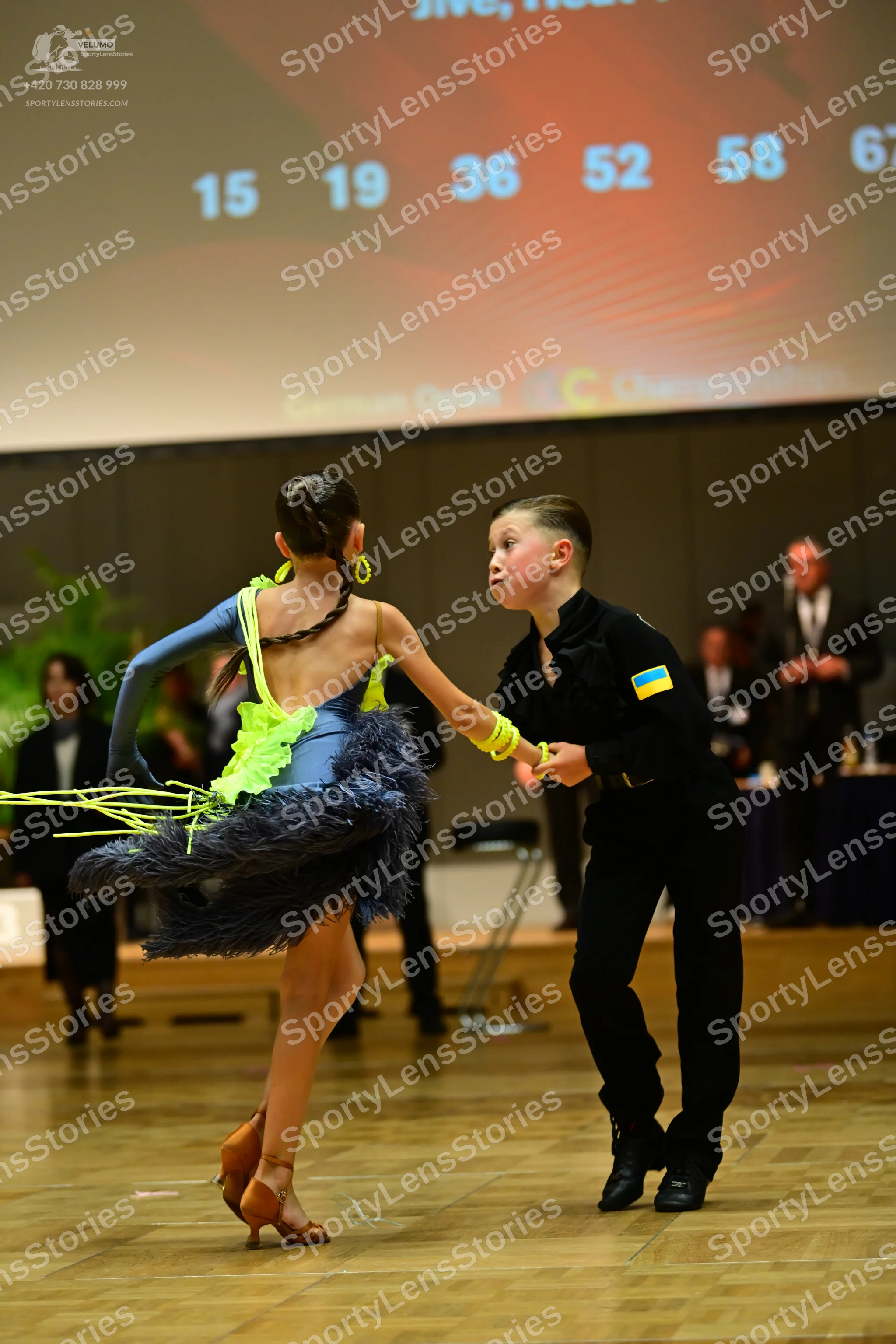 Dancesport competitor: Female dancer: blue and neon yellow Latin dance dress with a feathered/fringed s