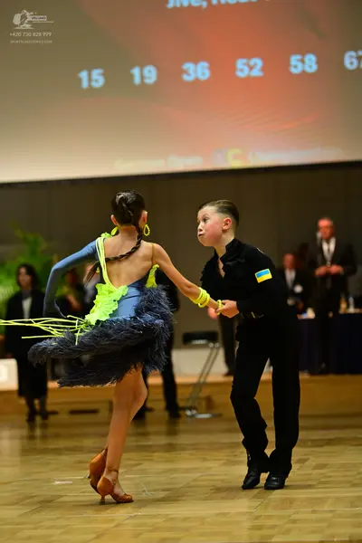 Dancesport competitor: Female dancer: blue and neon yellow Latin dance dress with a feathered/fringed s