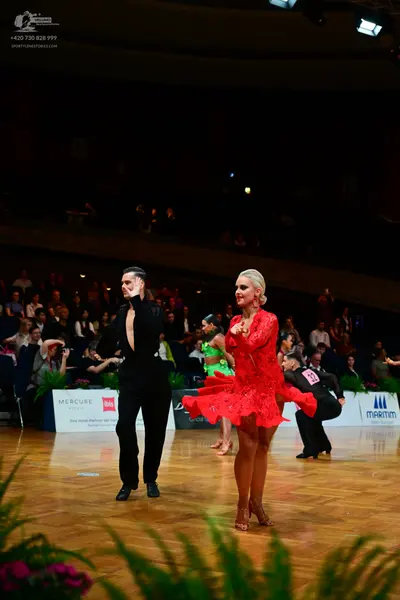 Dancesport competitor: Male dancer (foreground): black long-sleeved shirt and black trousers