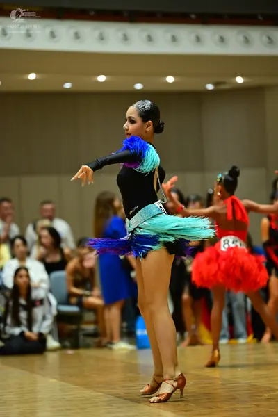Dancesport competitor #84: Female dancer in foreground: black long-sleeved latin dance dress with a volumin