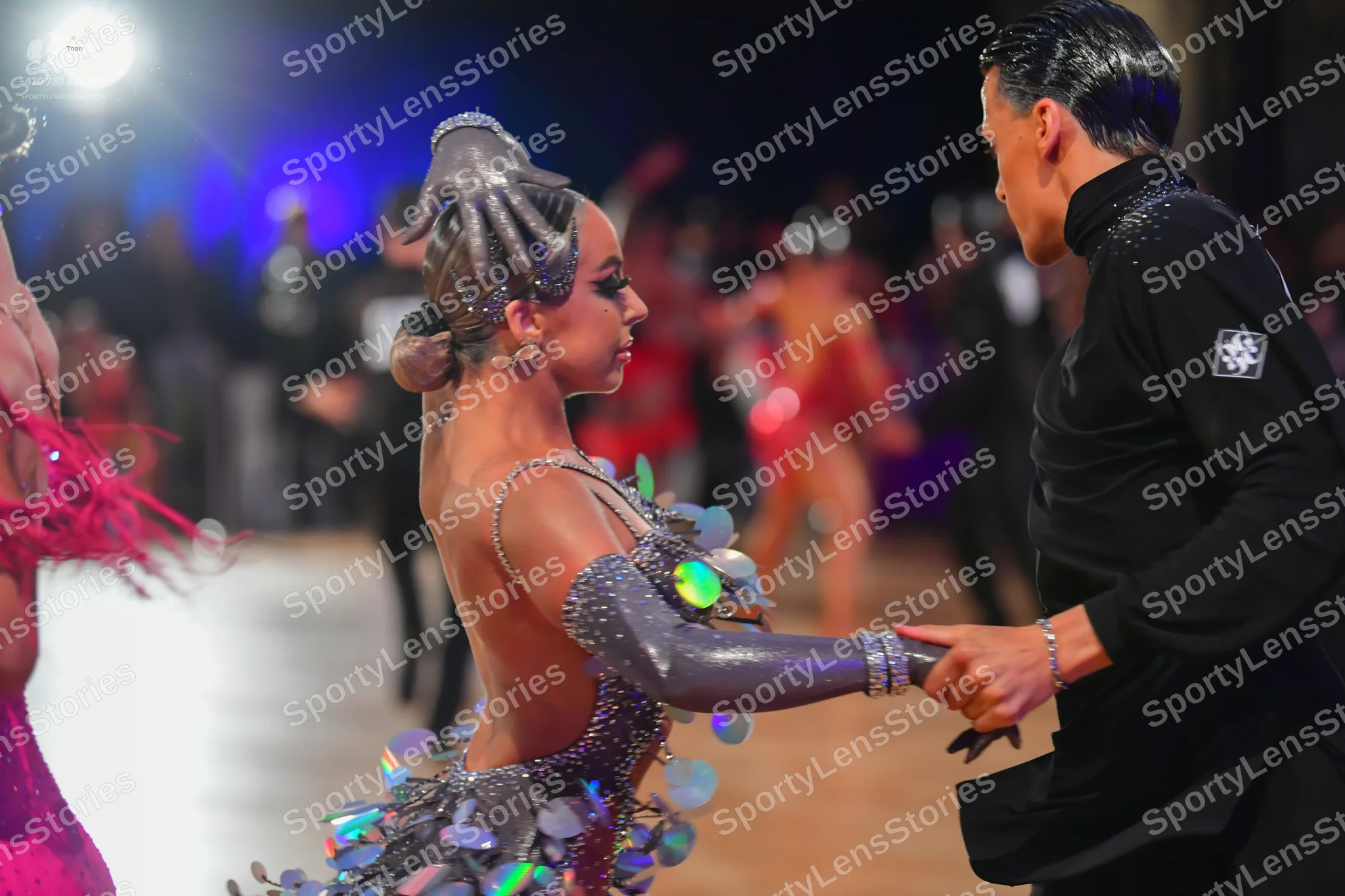 Dancesport competitor: Female dancer: grey/silver Latin dance costume featuring large, iridescent, circ