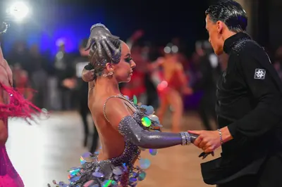 Dancesport competitor: Female dancer: grey/silver Latin dance costume featuring large, iridescent, circ