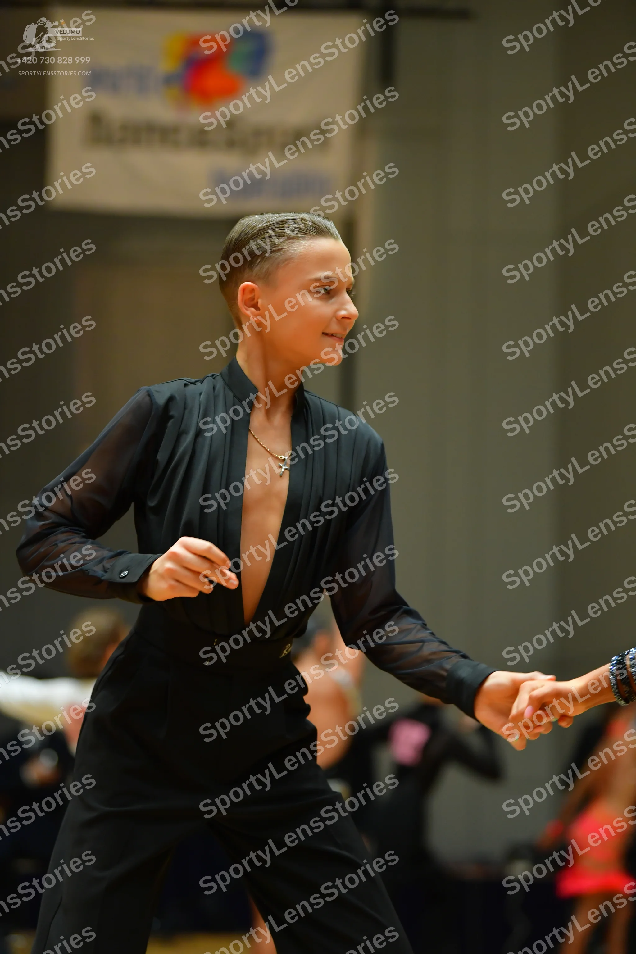 Dancesport competitor: Female dancer: black long-sleeved top with a deep V-neckline and black pants, we