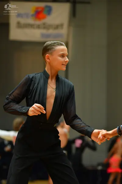 Dancesport competitor: Female dancer: black long-sleeved top with a deep V-neckline and black pants, we