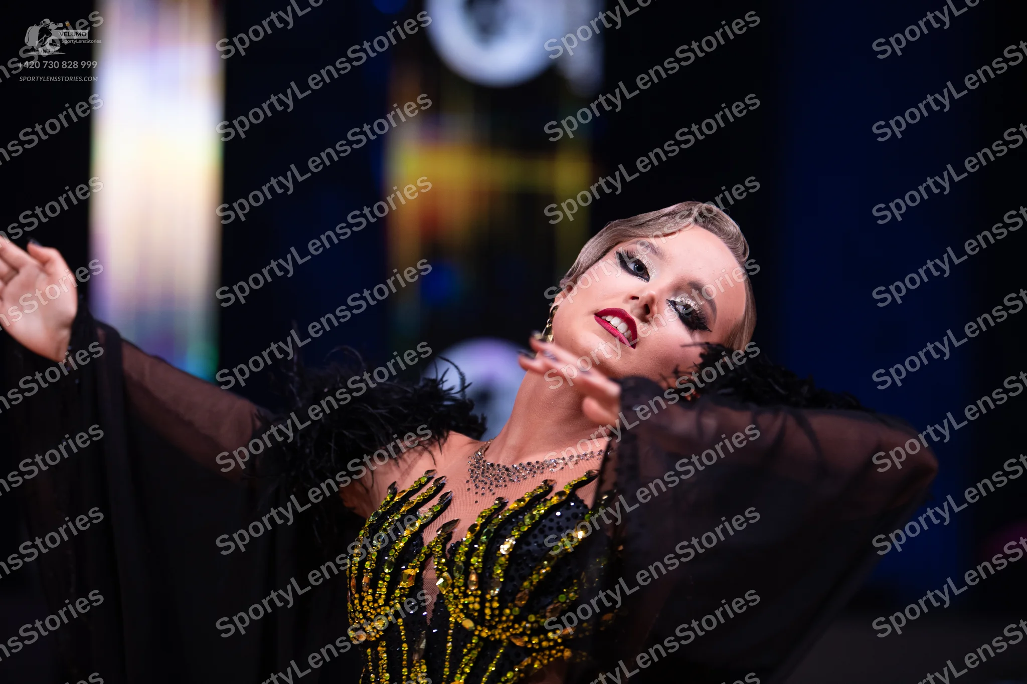 Dancesport competitor: Female dancer: black and gold sequined Latin dance bodice with sheer dark sleeve