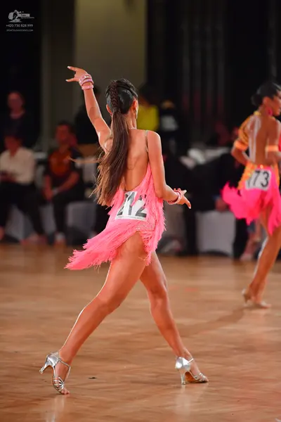 Dancesport competitor #12, #73: Female dancer 1: pink latin dress with fringe, backless, silver wristbands, and 