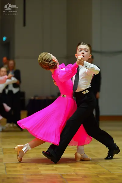 Dancesport competitor: Female dancer: bright pink long-sleeved ballroom dress with a full flowing skirt