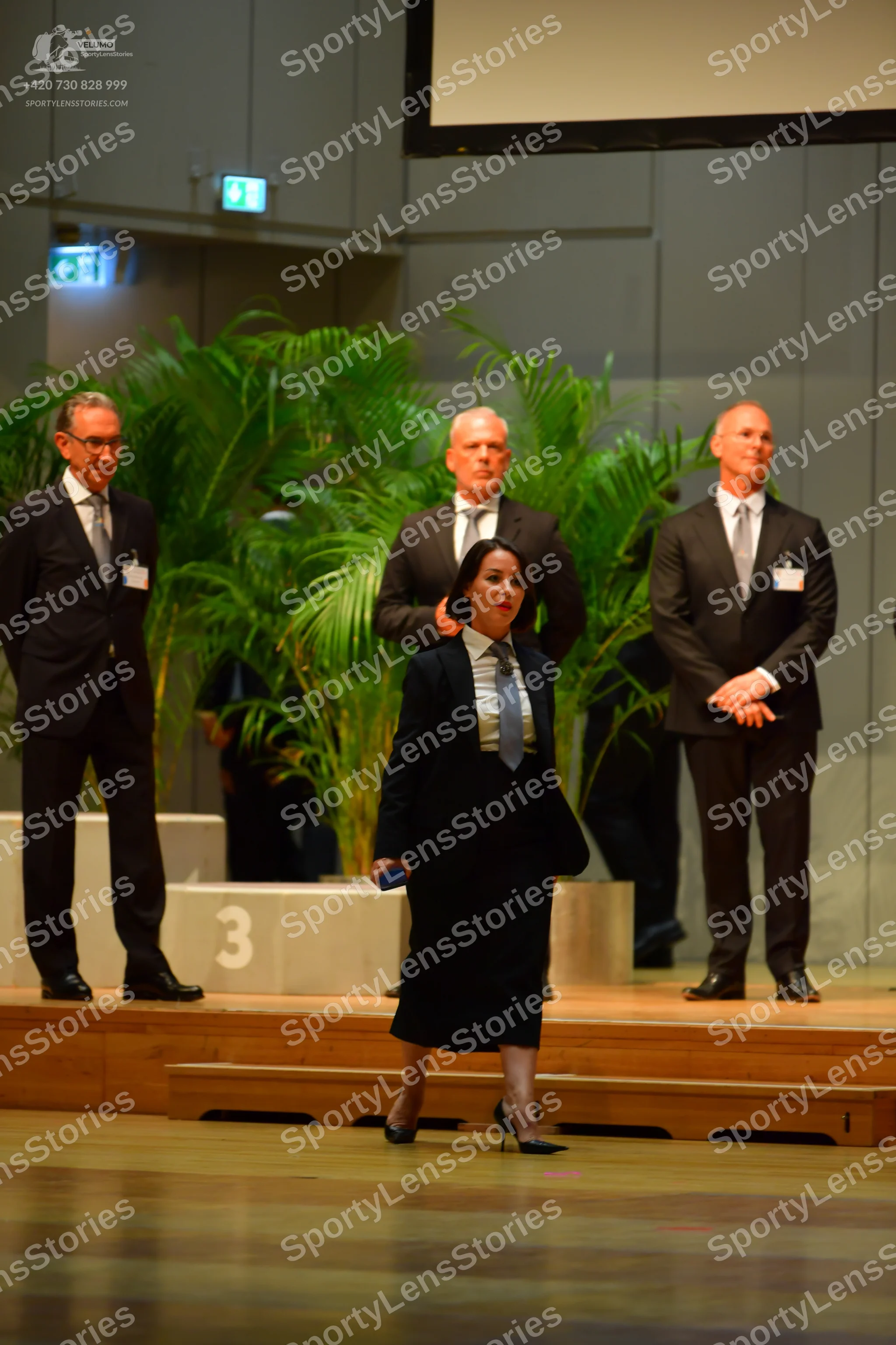 Dancesport competitor: No dancers are visible in the image; only officials in suits are present