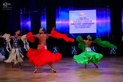 Dancesport competitor: First dancer: white Latin dress with blue and gold sequined bodice and a flowing