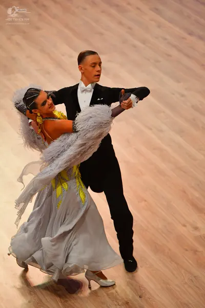 Dancesport competitor: Male dancer: black tuxedo with a white shirt and white bow tie