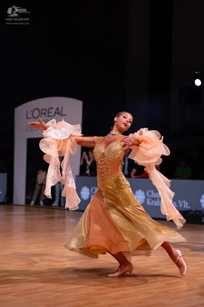 Dancesport competitor: Female dancer: champagne-colored ballroom dress with a sequined bodice and large
