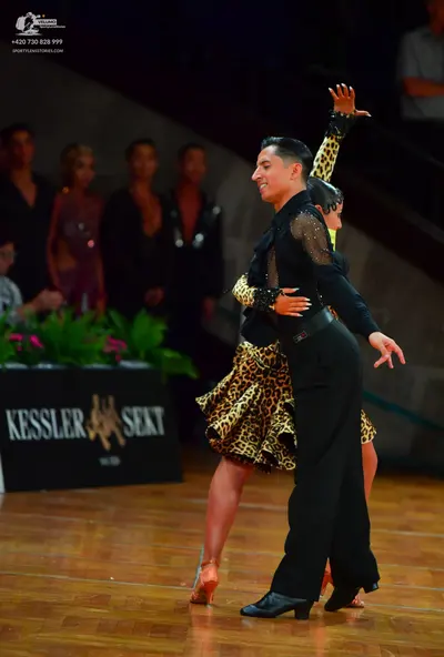 Dancesport competitor: Male dancer: black long-sleeved shirt with sheer mesh panels on the arms and bla
