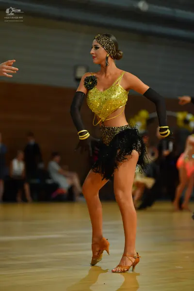 Dancesport competitor: Female dancer: gold sequin halter-style top with black floral applique, leopard 