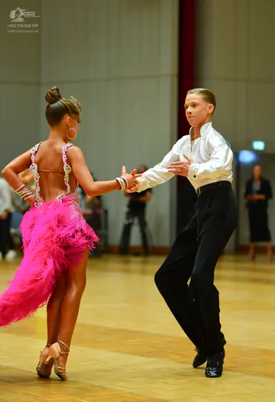 Dancesport competitor: Female dancer: bright pink latin dress with feather fringe and sequined straps, 