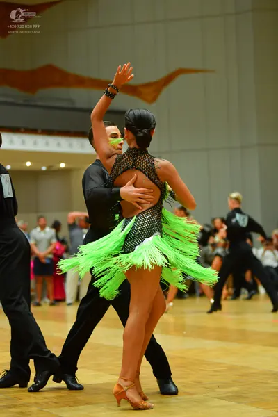 Dancesport competitor: Female dancer: lime green and black Latin dress with a mesh top and long lime gr