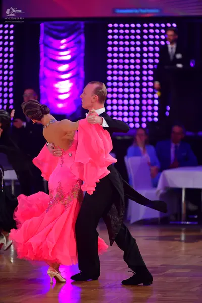 Dancesport competitor: Female dancer: bright pink ballgown with a voluminous, ruffled tulle skirt and a
