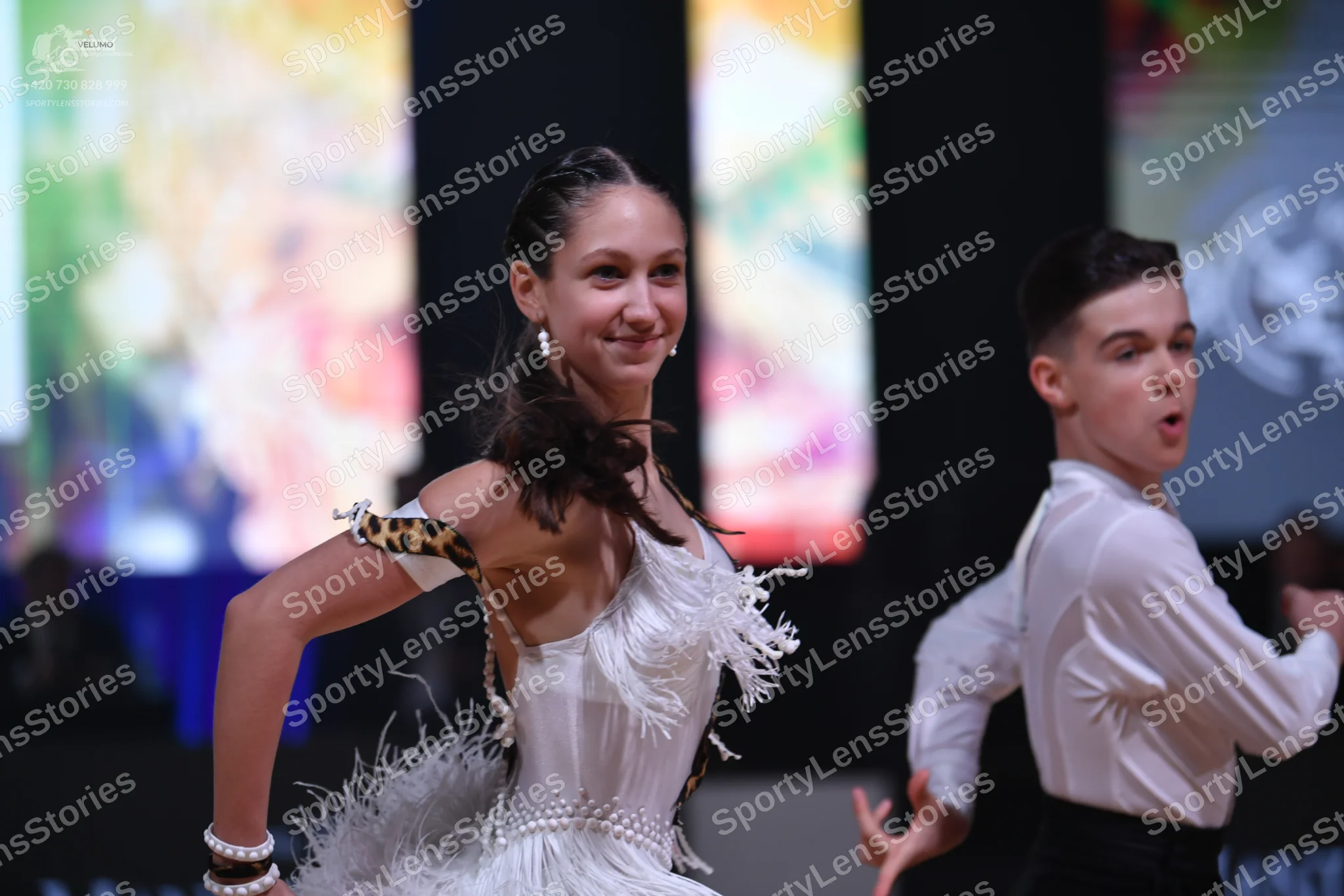 Dancesport competitor: Female dancer: white Latin dress with fringe and a leopard print detail on the s