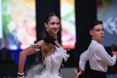 Dancesport competitor: Female dancer: white Latin dress with fringe and a leopard print detail on the s