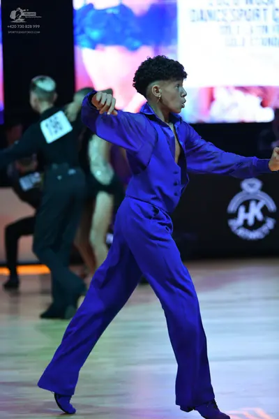 Dancesport competitor: Male dancer (foreground): blue/purple long-sleeved shirt and trousers in a smoot