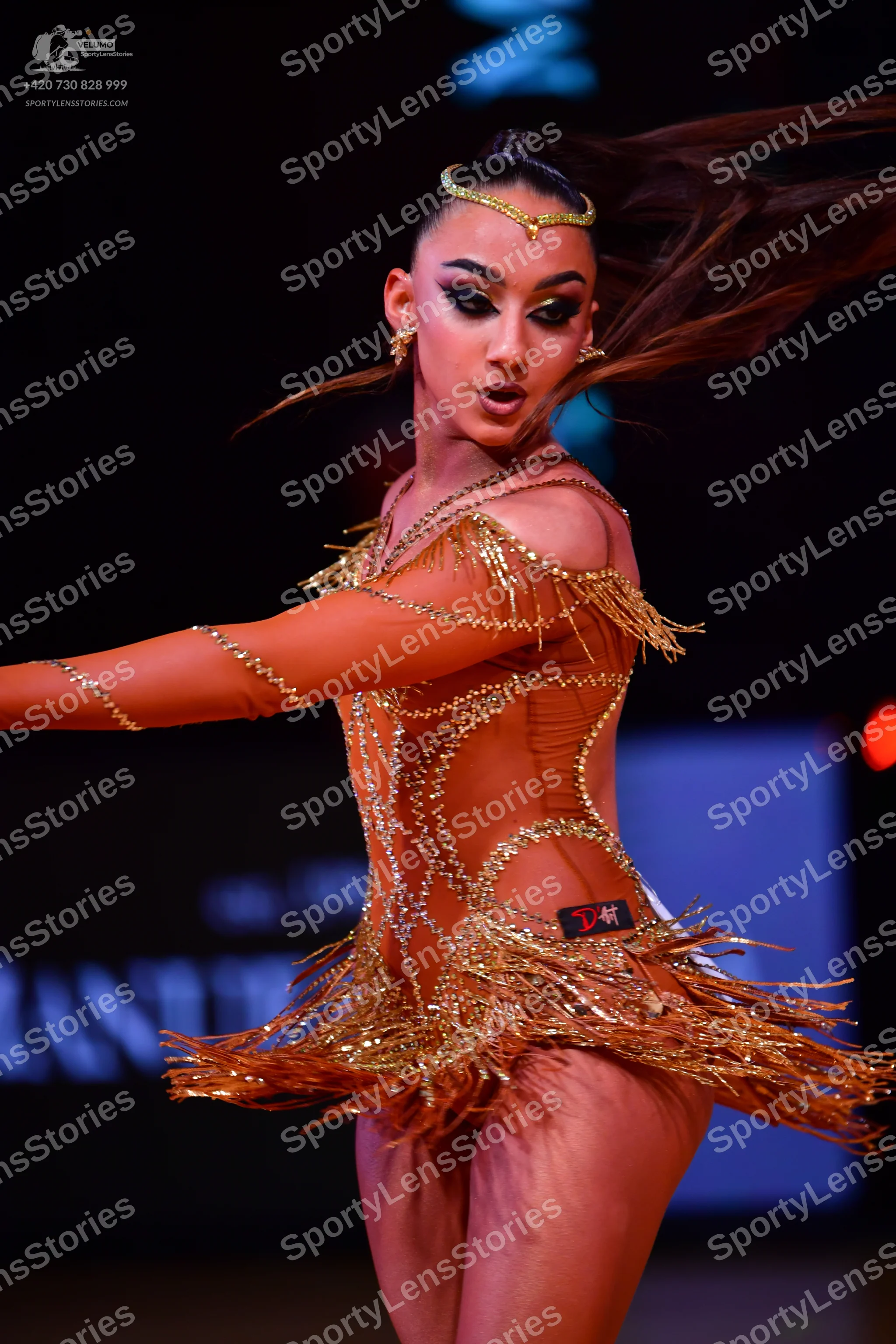 Dancesport competitor: Female dancer: bronze latin dress with nude mesh, metallic/sequin patterns, and