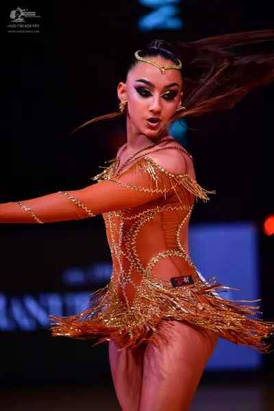 Dancesport competitor: Female dancer: bronze latin dress with nude mesh, metallic/sequin patterns, and 