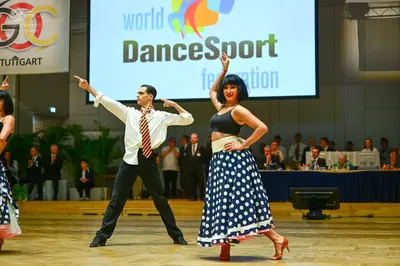Dancesport competitor: Male dancer: white long-sleeved shirt, red and white patterned tie, and black tr