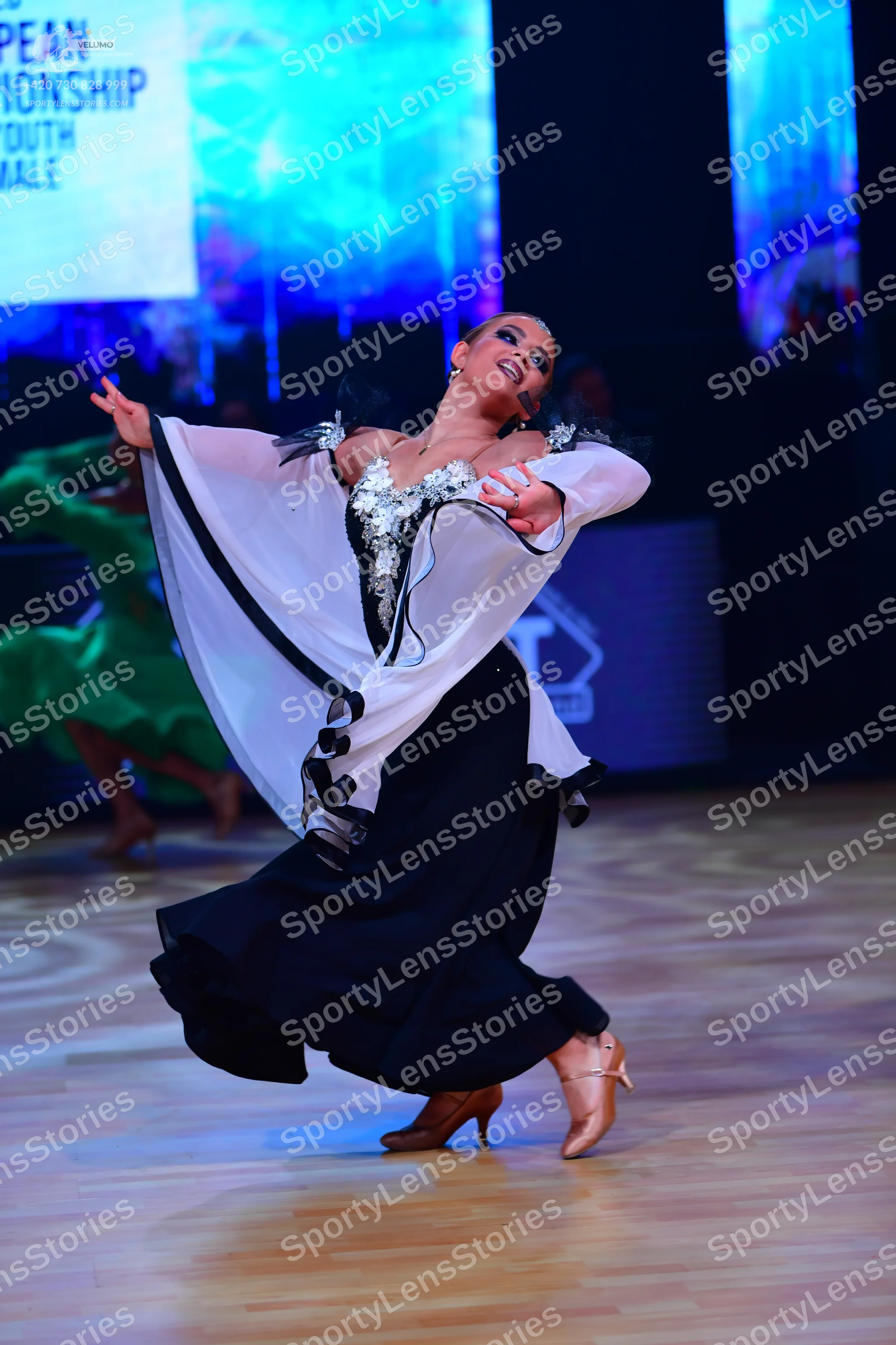 Dancesport competitor: Female dancer in foreground: white and black ballroom dress with a sequined bodi