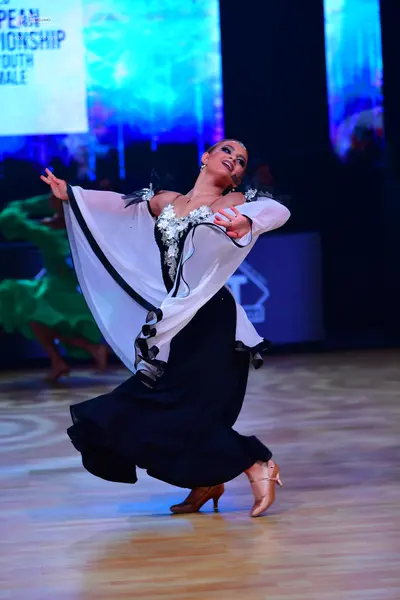 Dancesport competitor: Female dancer in foreground: white and black ballroom dress with a sequined bodi