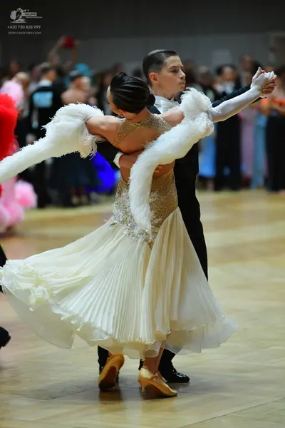 Dancesport competitor: Female dancer: cream-colored ballroom dress with a sequined bodice, a large plea