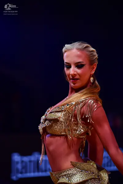 Dancesport competitor: Female dancer: gold sequined two-piece Latin costume with fringe on the top and 