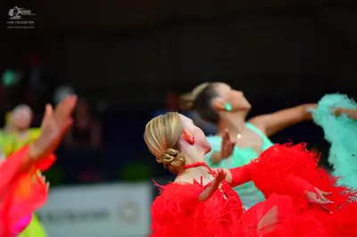 Dancesport competitor: Female dancer in foreground: red latin dress with heavy fringe