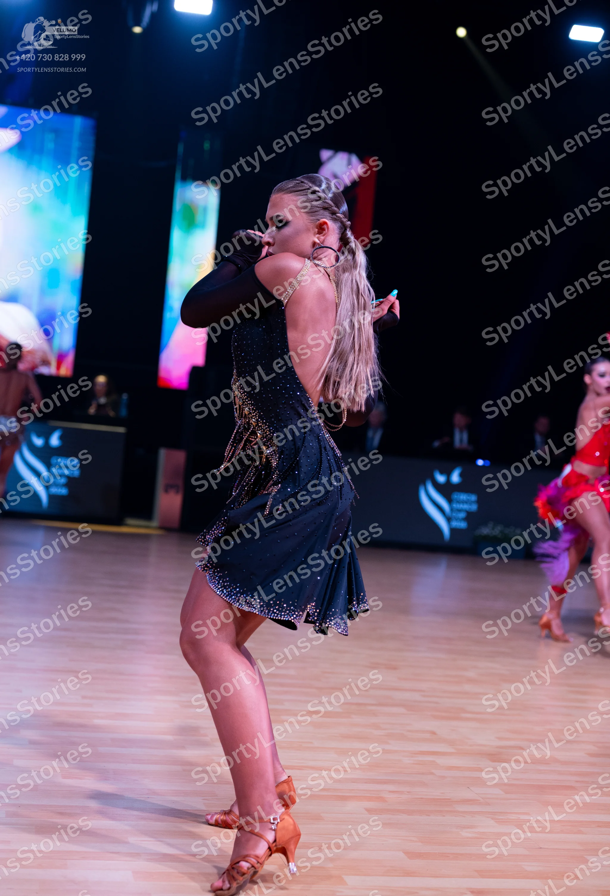 Dancesport competitor: Female dancer (foreground): black Latin dance dress with small sparkly embellish