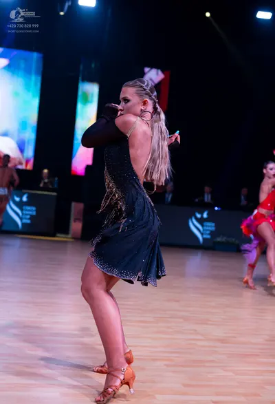 Dancesport competitor: Female dancer (foreground): black Latin dance dress with small sparkly embellish