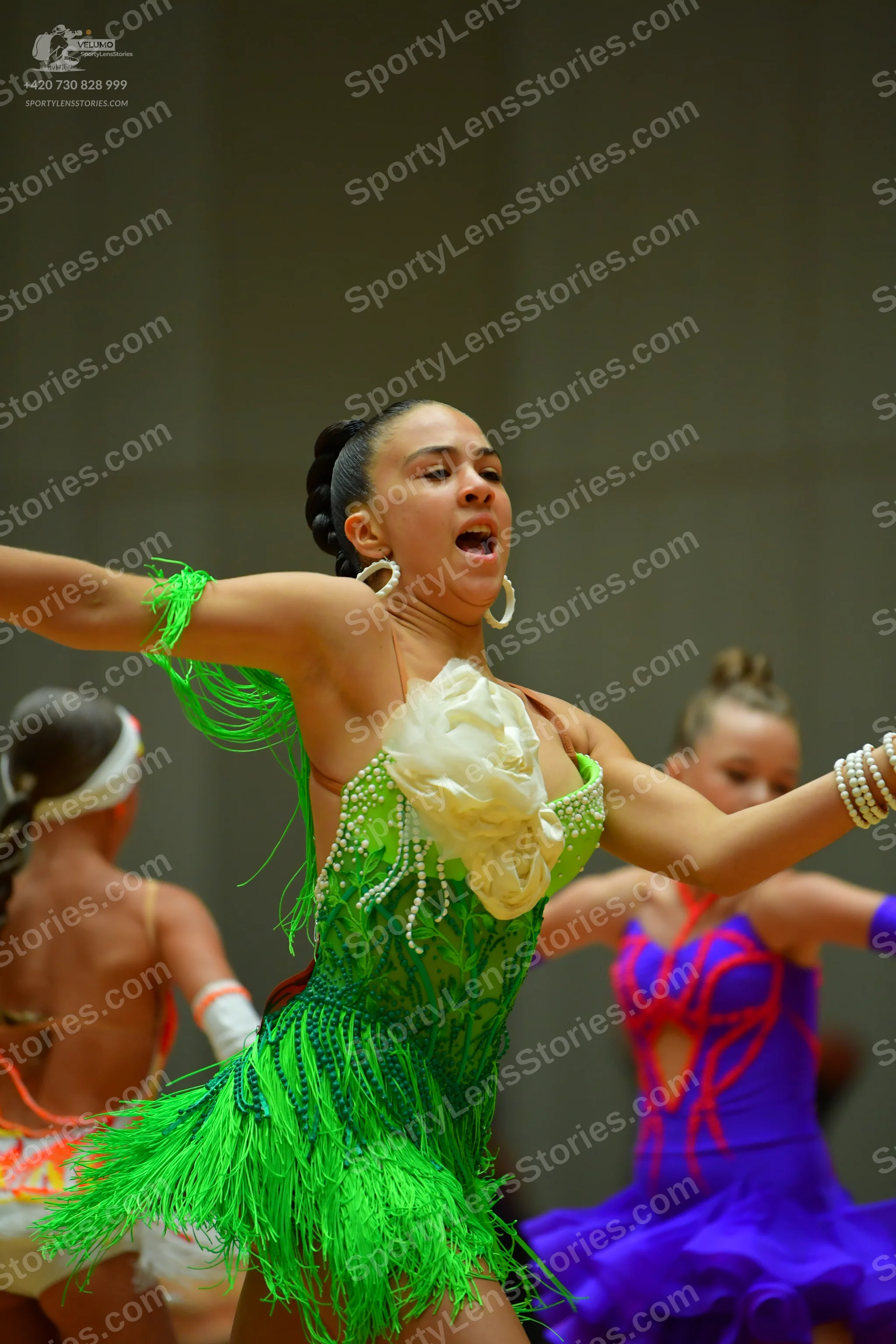 Dancesport competitor: Female dancer in foreground: lime green latin dress with long fringe, sequined b