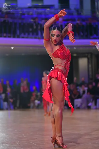 Dancesport competitor: Female dancer: red Latin dress with a sequined/beaded top and an asymmetric skir