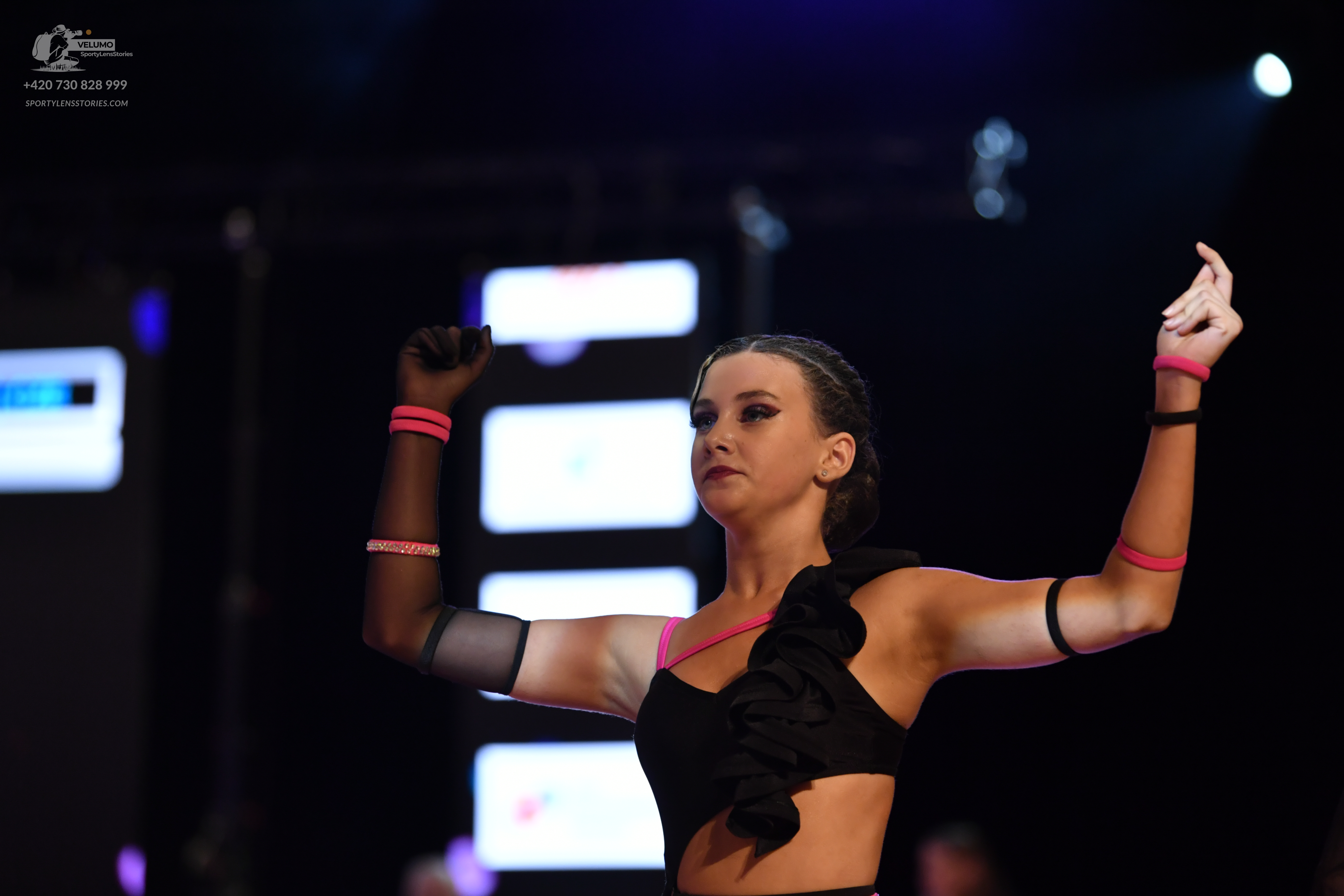 Dancesport competitor: Female dancer: black crop top with ruffles and pink trim, and matching black and