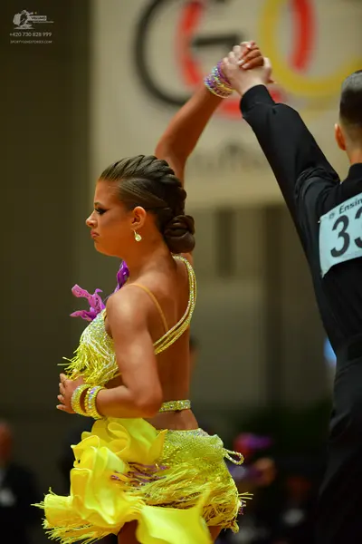Dancesport competitor: Female dancer: yellow sequined Latin dress with yellow and purple fringe, and sp