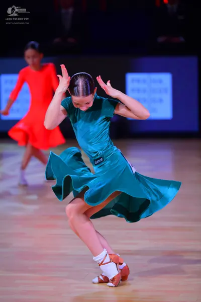 Dancesport competitor: Female dancer in foreground: teal satin Latin dance dress with short sleeves and