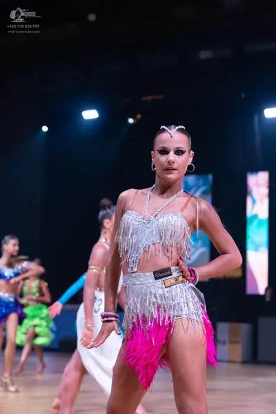 Dancesport competitor: Female dancer: silver sequin latin dress with pink fringe at the hem