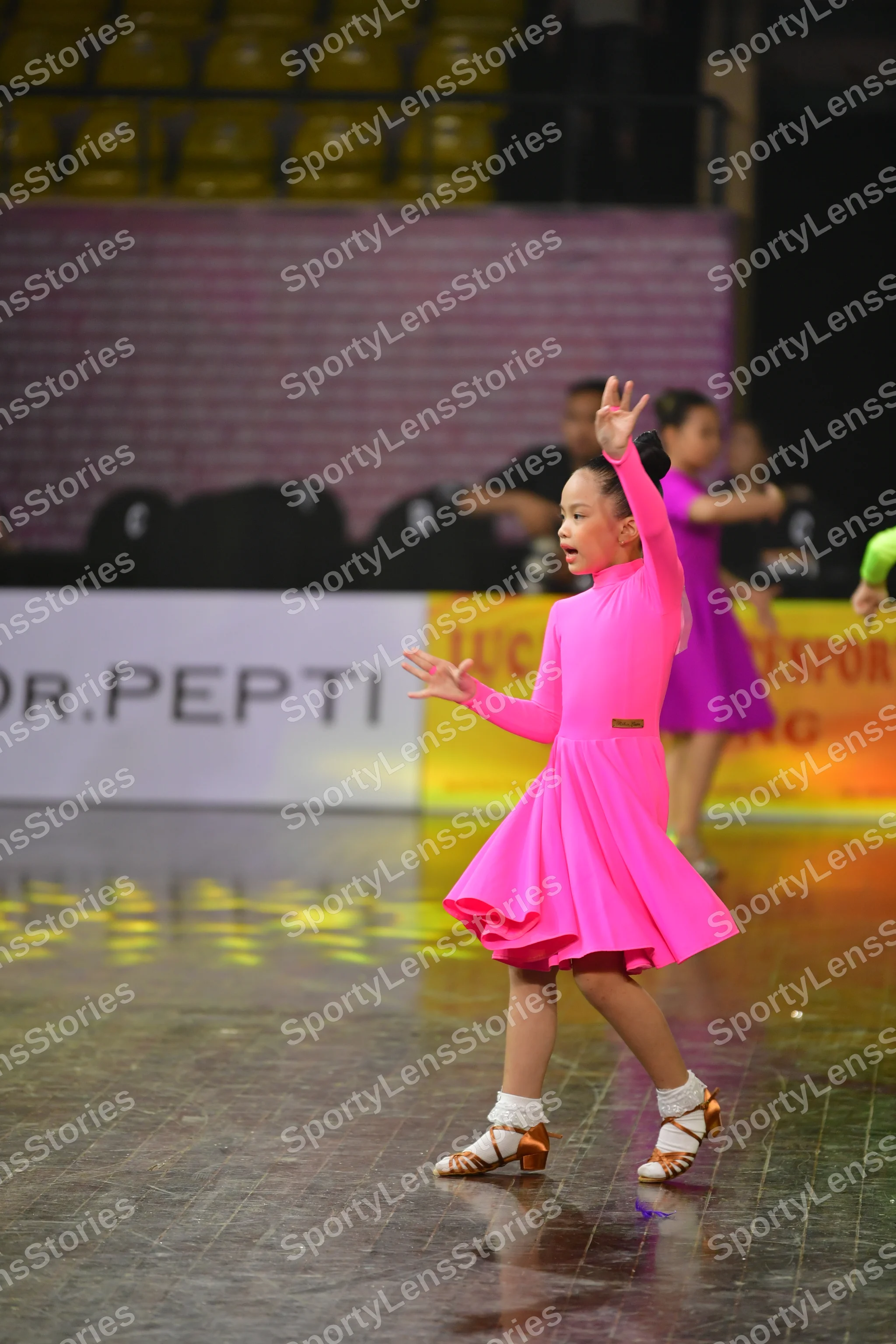 Dancesport competitor: Female dancer 1: bright pink, long-sleeved Latin dance dress with a short, flare