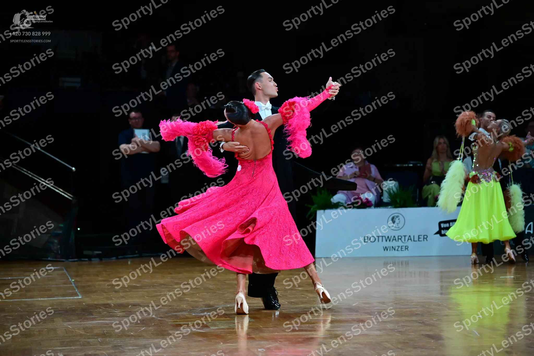 Dancesport competitor: Female dancer 1: hot pink Latin dress with large ruffled sleeves and a flared sk