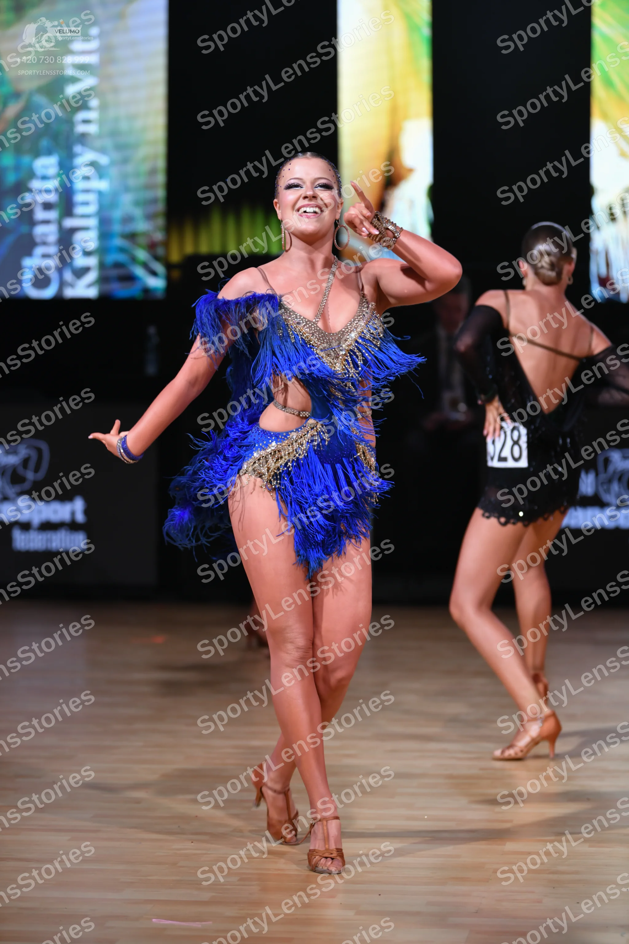 Dancesport competitor: Female dancer in foreground: blue and gold latin dress with fringe and sequins